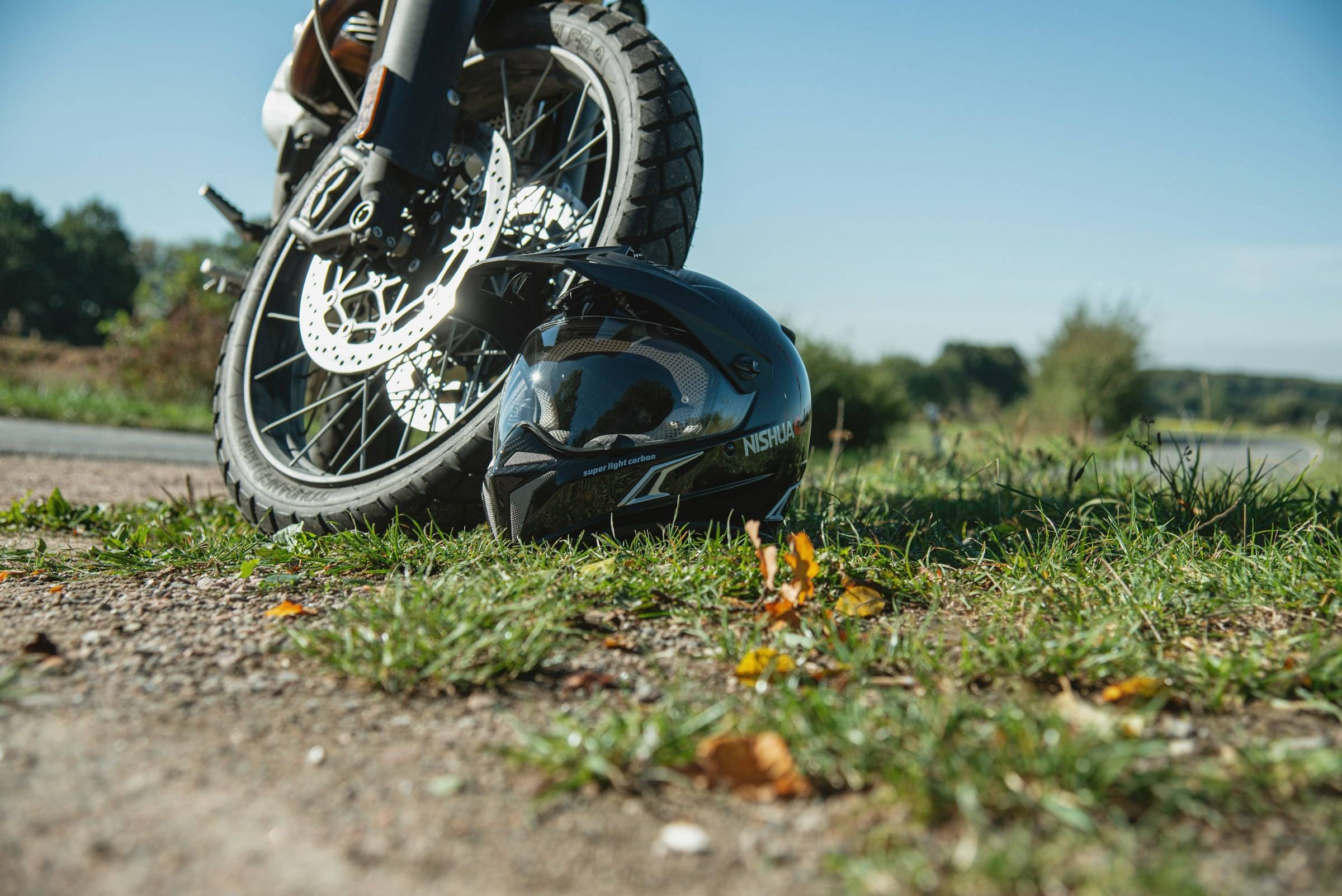 A motorcycle lying on its side on the grass at the edge of a road